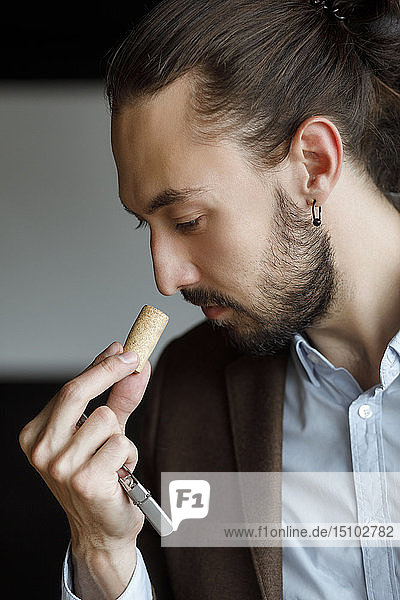 Young man smelling wine on cork at tasting