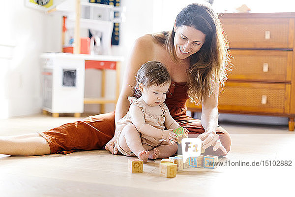 Woman and her baby daughter playing with toy blocks