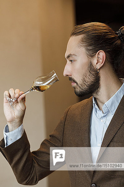 Junger Mann riecht an Wein im Glas bei einer Verkostung