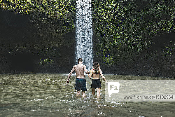 Junges Paar hält sich im Fluss am Tibumana-Wasserfall in Bali  Indonesien