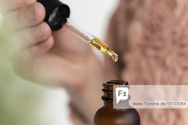 Hand of woman holding pipette of beauty oil