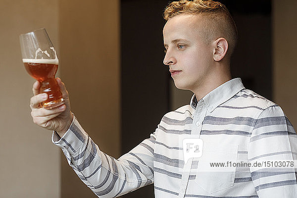 Junger Mann untersucht ein Glas Bier