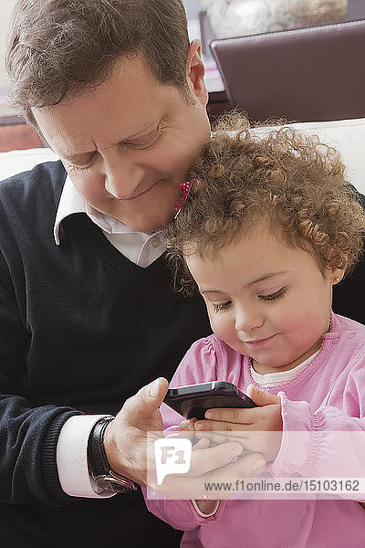 Vater und Tochter benutzen ein Smartphone