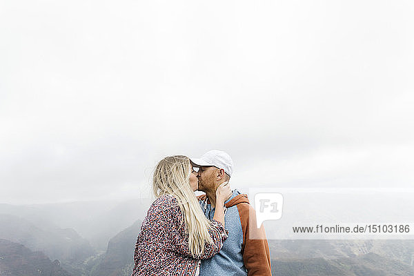 Mid erwachsenen Paar küssen von Bergen im Nebel