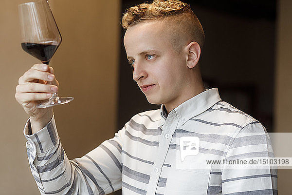 Junger Mann begutachtet ein Glas Wein