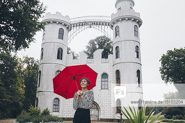 Woman holding red umbrella by Schloss Pfaueninsel in Potsdam  Germany