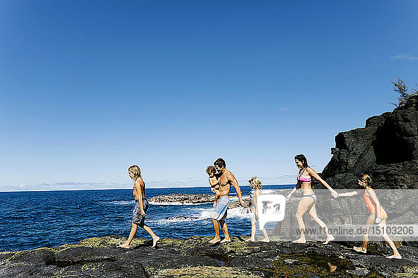 Familie spaziert auf Felsen am Meer