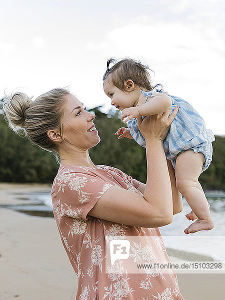 Woman holding baby daughter on beach