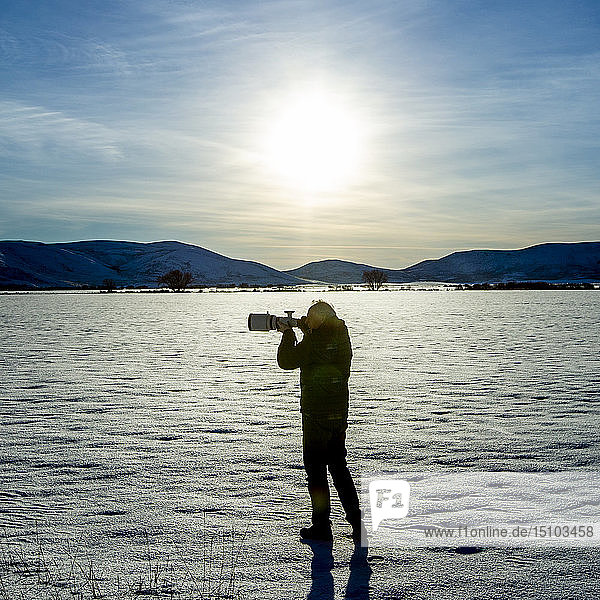 Senior man photographing in snow field in Picabo  Idaho