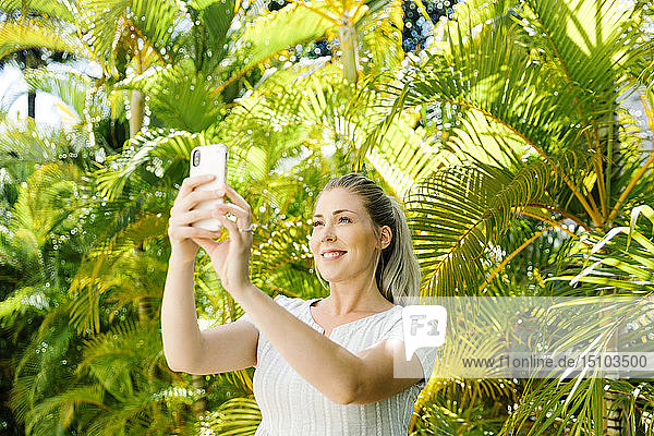Frau nimmt Selfie von Palmen