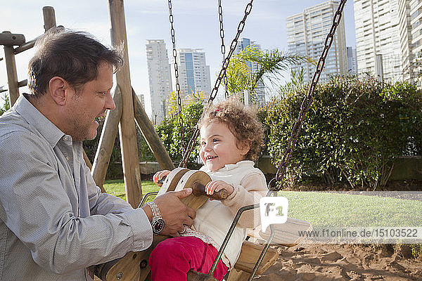 Vater mit Tochter auf einer Schaukel im Stadtpark