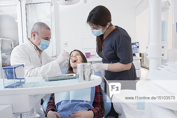 Zahnarzt und Zahnhygienikerin reinigen die Zähne eines Patienten