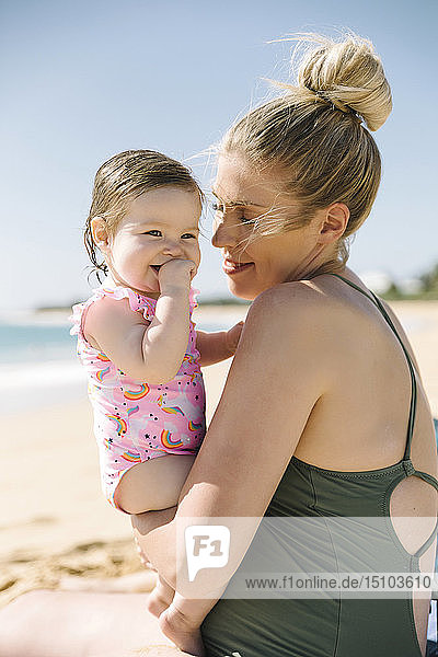 Mutter trägt ihr kleines Mädchen am Strand