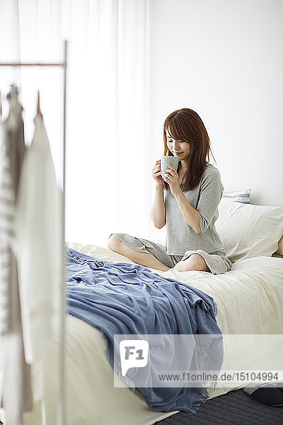 Junge japanische Frau im Bett am Morgen