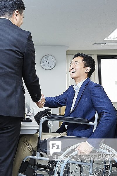 Japanischer junger Mann im Rollstuhl bei der Arbeit