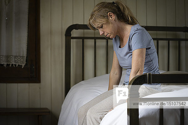 Nachdenkliche  traurige Frau auf dem Bett sitzend