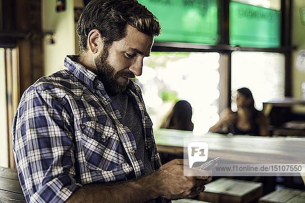 Mann benutzt Smartphone in einer Bar
