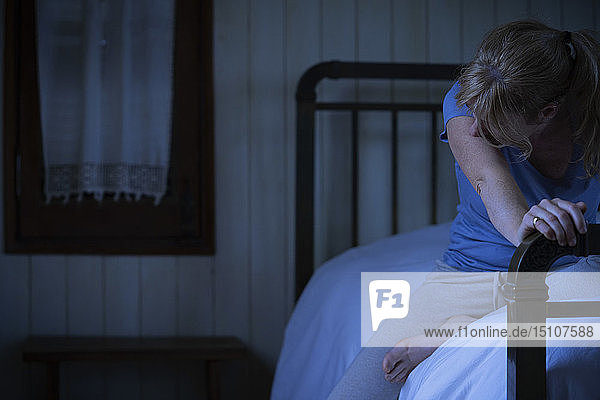 Besorgte Frau auf dem Bett sitzend