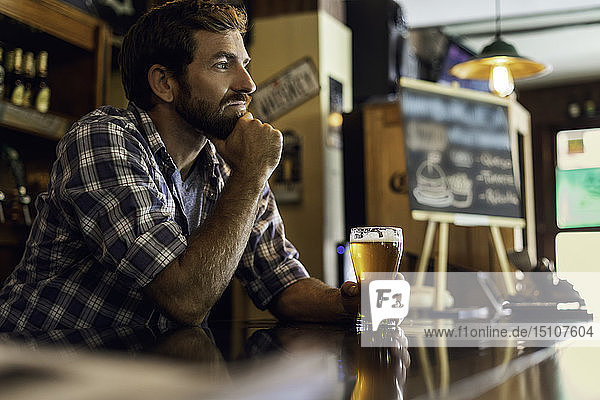 Thoughtful man holding glass of beer