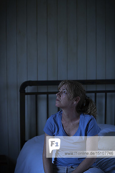 Nachdenkliche  traurige Frau auf dem Bett sitzend
