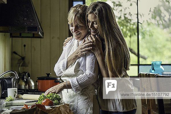 Tochter  die ihre Mutter in der Küche umarmt