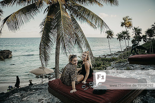 Mexiko  Quintana Roo  Tulum  zwei glückliche junge Frauen entspannen sich am Strand