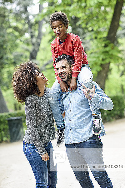 Glückliche Familie beim Spaziergang im Park  Vater trägt Sohn huckepack