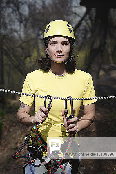 Junge Frau mit gelbem T-Shirt und Helm in einem Seilgarten