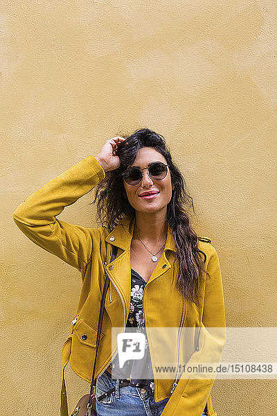 Porträt einer jungen Frau mit gelber Lederjacke und Sonnenbrille
