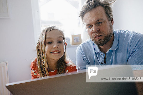 Vater und Tochter benutzen Laptop zu Hause