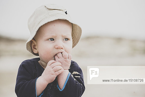 Baby boy eating sand on the beach