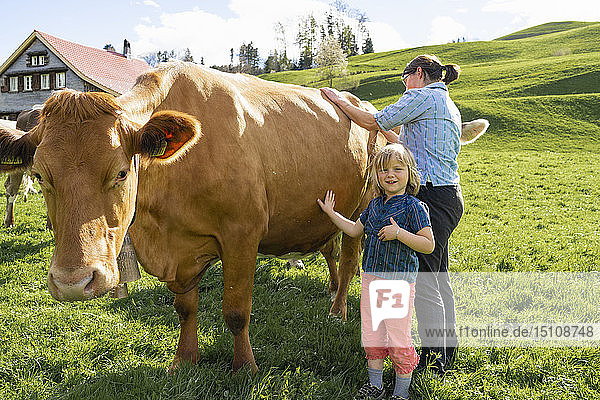 Porträt eines Mädchens mit Mutter  die eine Kuh auf der Weide hütet