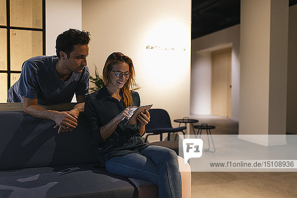 Junger Mann und Frau benutzen Tablette auf der Couch