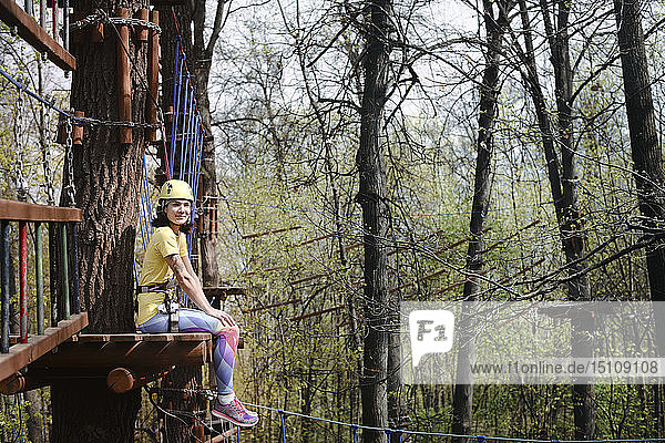 Young woman sitting on a platform in a rope course