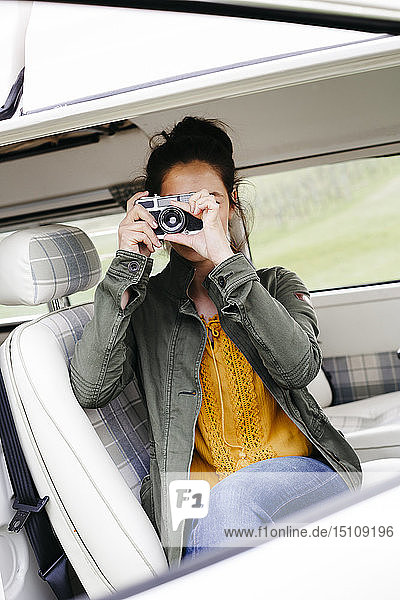 Young woman sitting in camper  taking pictures