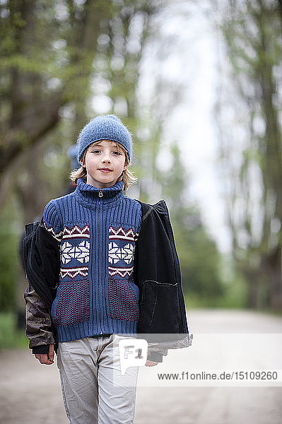 Porträt eines Jungen mit blauem Hut und Pullover in einem Park