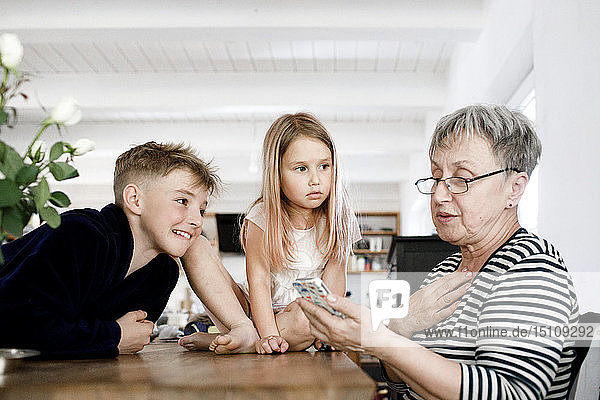 Großmutter und Enkelkinder telefonieren zu Hause
