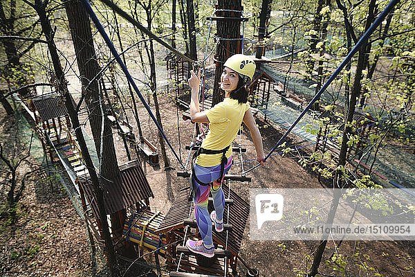 Young woman wearing yellow t-shirt and helmet in a rope course