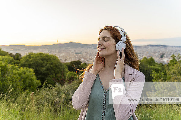 Junge rothaarige Frau mit Kopfhörern am Aussichtspunkt