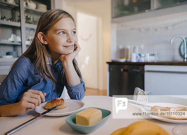 Smiling girl at home sitting at breakfast table