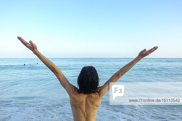 Seychellen  Rückenansicht eines Mannes mit vor dem Meer erhobenen Armen