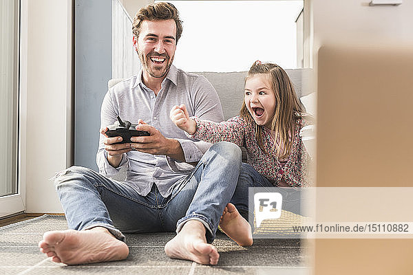Young man and little girl playing computer game with gaming console