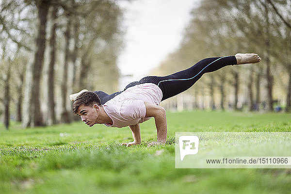 Junger Mann macht Gymnastikakrobatik in einem städtischen Park