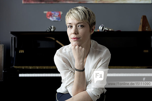 Porträt einer Frau  die in ihrem Musikzimmer vor dem Klavier sitzt