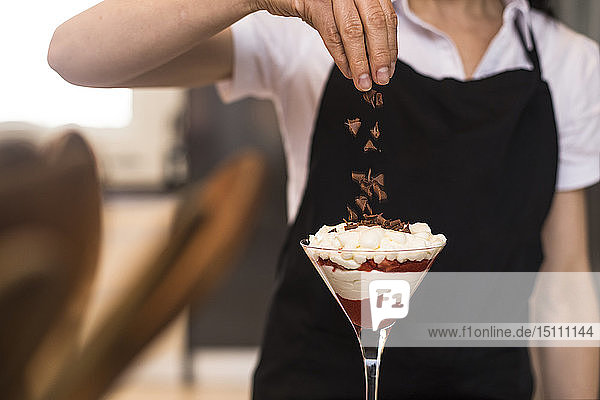 Nahaufnahme einer Frau  die in der Küche Schokolade auf ein Dessert gießt