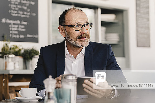 Mature businessman using tablet in a cafe