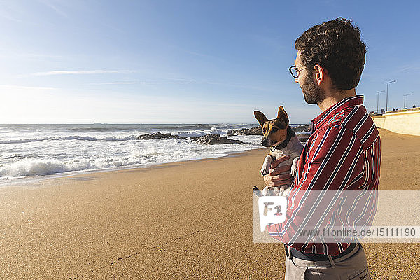 Portugal  Porto  zufriedener junger Mann am Strand mit seinem Hund