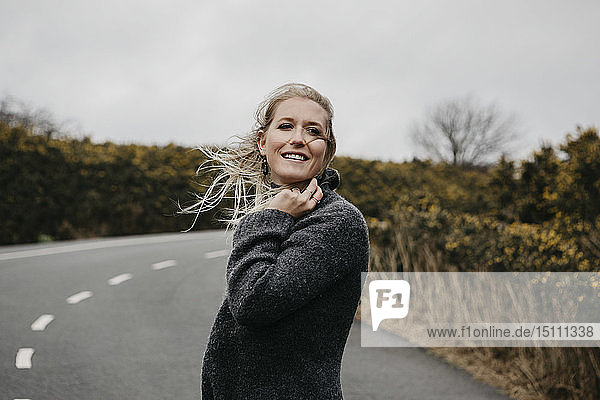 UK  Schottland  Isle of Skye  lächelnde junge Frau auf Landstraße