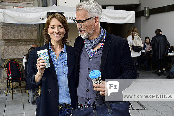 Portrait of smiling mature couple with reusable bamboo cups in the city