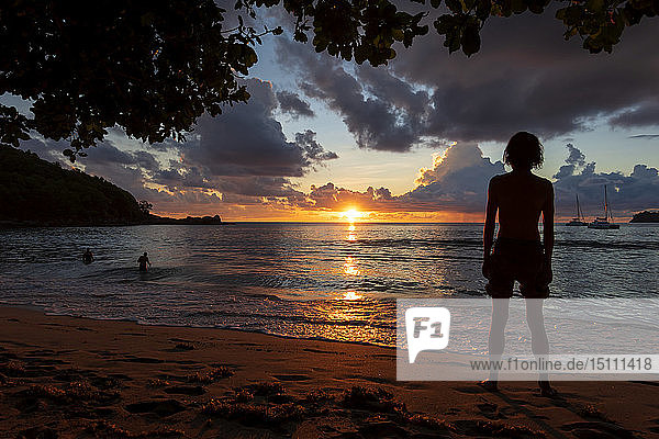 Seychellen  Mahe  Takamaka Beach  Silhouette eines Mannes  der am Strand steht und den Sonnenuntergang betrachtet
